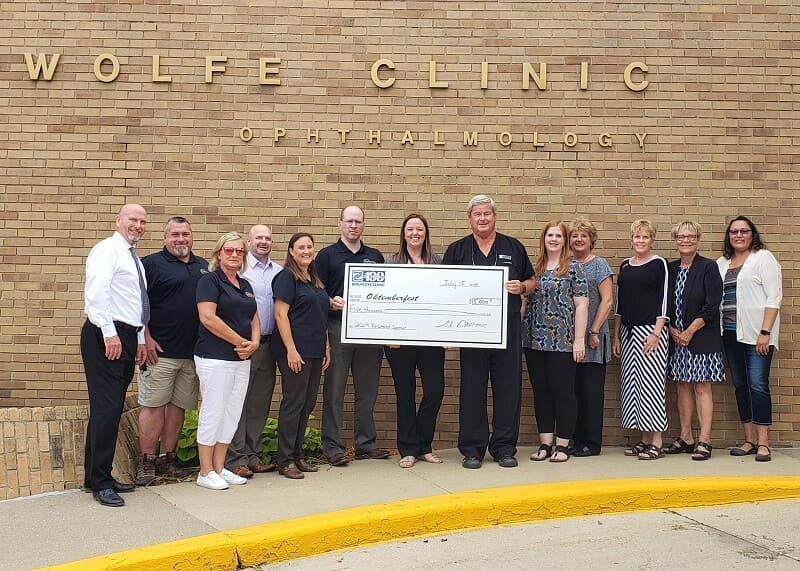 Wolfe Eye Clinic staff presenting Marshalltown Oktemberfest sponsorship check in Marshalltown, Iowa.