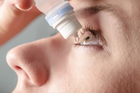 Patient placing eye drops on cornea to hydrate eyes and relieve dry eye symptoms at Wolfe Eye Clinic.